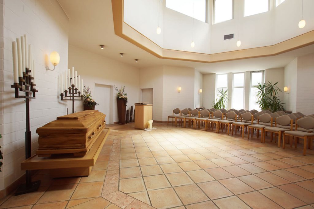 Die helle Gerricus-Kapelle von Vogt & Kamp Bestatter Düsseldorf mit Sarg, Sitzreihen und stilvoller Dekoration für Bestattung Düsseldorf.