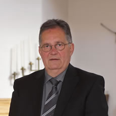 Ein Bestatter Düsseldorf im Anzug steht in der stimmungsvoll beleuchteten Gerricus-Kapelle bei einer Bestattung Düsseldorf.