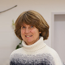 Eine freundlich lächelnde Frau, Mitarbeiterin bei Vogt & Kamp Bestatter Düsseldorf, in modernen Innenräumen des Bestattungshauses.