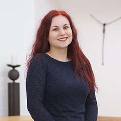 Eine freundliche Mitarbeiterin von Vogt & Kamp Bestattungen Düsseldorf lächelt in stilvoller Innenraumkulisse des Bestattungshauses.