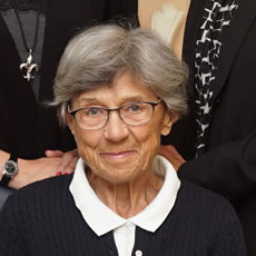 Eine ältere Dame lächelt freundlich, zwei Personen stehen hinter ihr - einfühlsame Begleitung durch Bestatter Düsseldorf.