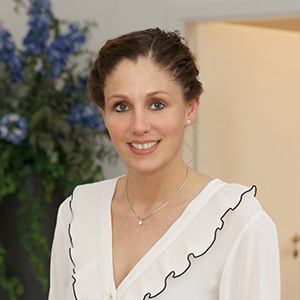 Mitarbeiterin von Vogt & Kamp Bestattungen Düsseldorf lächelt freundlich im stilvollen Innenraum mit Blumen, Bestattung Düsseldorf.