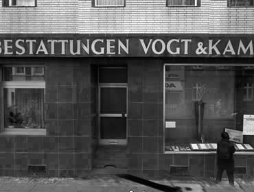 Schwarz-weiß-Foto vom Bestattungshaus Vogt & Kamp, Bestatter Düsseldorf, mit Person vor Aushang, Bestattung Düsseldorf.